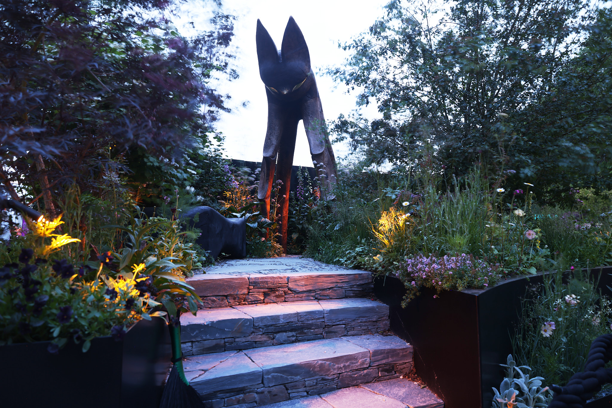 The Nocturnal Garden at dusk during RHS Chelsea Flower Show 2026, with Hudson Lighting's 1800K dark sky compliant fittings illuminating the planting and pathway